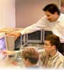 students and teacher pointing at computer screen and discussing
